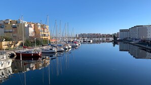 A marina with boats docked, buildings in the background, and calm water reflecting the scene. - Saint pierre home Sea + terrace and panoramic mediterrannée. (Fleury)