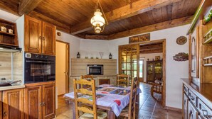 Una cocina rústica con armarios de madera, una mesa de comedor con sillas y una lámpara colgante.
