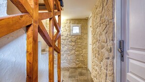 Un estrecho pasillo con paredes de piedra y estructura de vigas de madera.