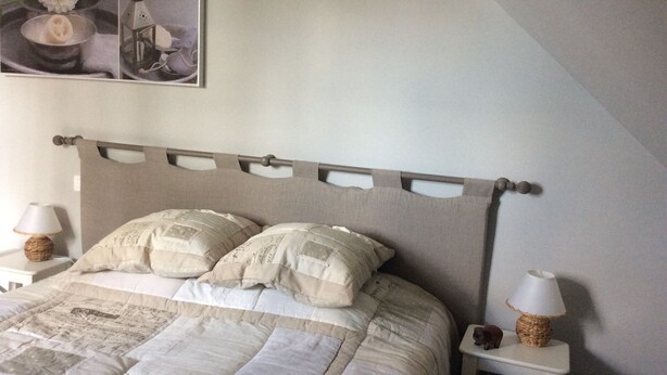 Una camera da letto con un letto, due comodini, una lampada e un elemento decorativo a parete.