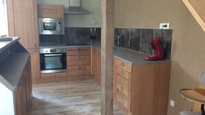 Una cucina compatta con mobili in legno, un forno a microonde, un forno e un piano cottura a gas.