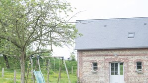 Un edificio in mattoni con una porta bianca e finestre, uno scivolo verde e un albero sullo sfondo.