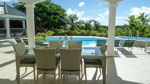 An outdoor seating area with wicker chairs and a glass table, overlooking a swimming pool and lush greenery. - Not to miss! Beautiful and large villa very nice, all comfort and jacuzzi (LE FRANCOIS)