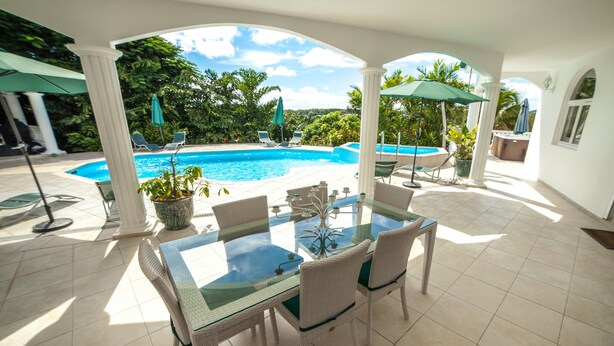A covered outdoor area with a glass table and chairs, a pool, and umbrellas. - Not to miss! Beautiful and large villa very nice, all comfort and jacuzzi (LE FRANCOIS)