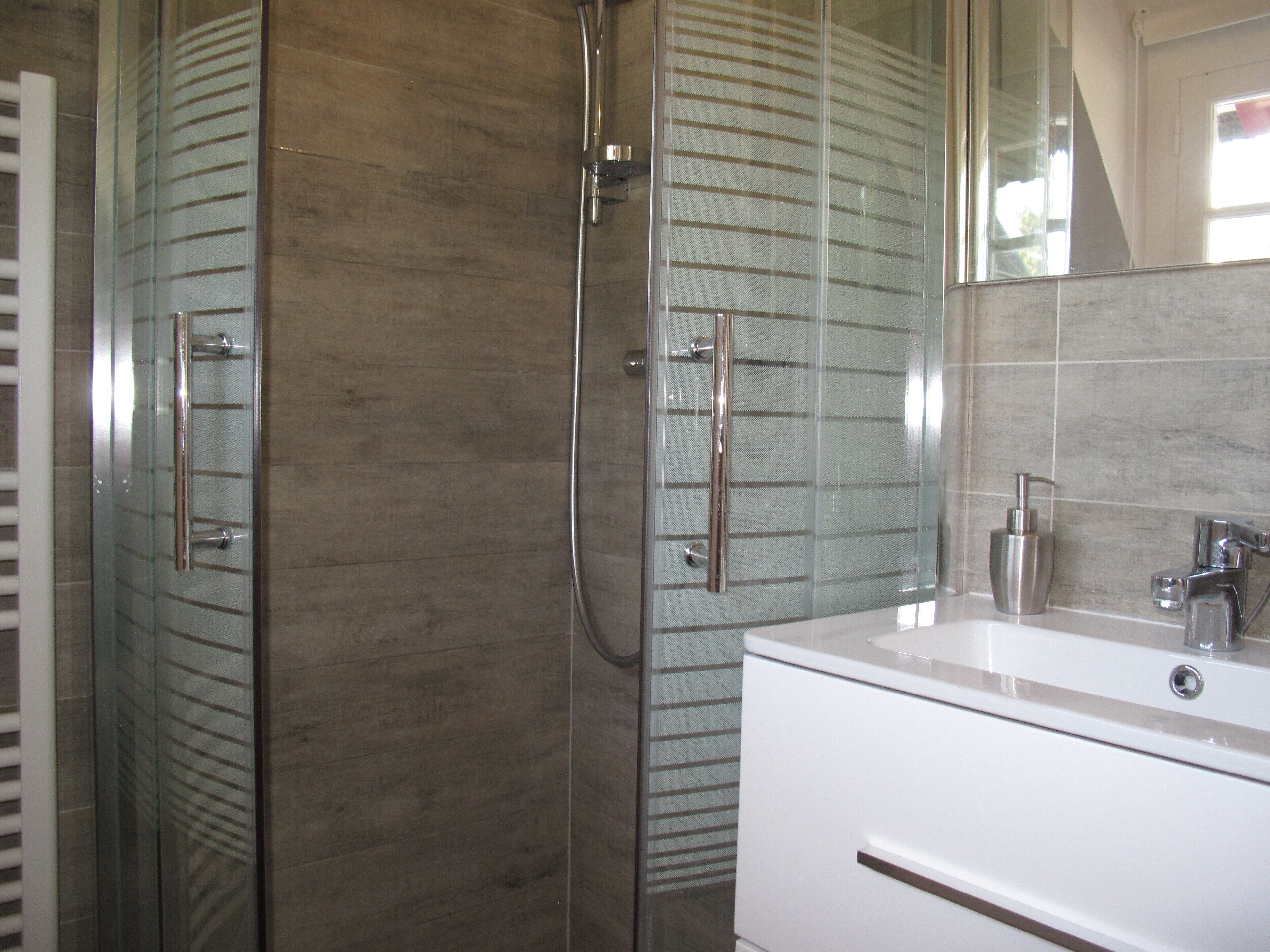 A bathroom with a glass-enclosed shower, a white sink, and a mirror.