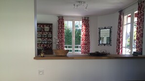 Eine Küche mit einer Holzausziehtheke, einem Korb, einem Dekoartikel und einem Fenster mit floralen Vorhängen.