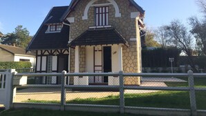 Ein Haus aus Stein mit Satteldach und Schornstein, umgeben von einem weißen Zaun.
