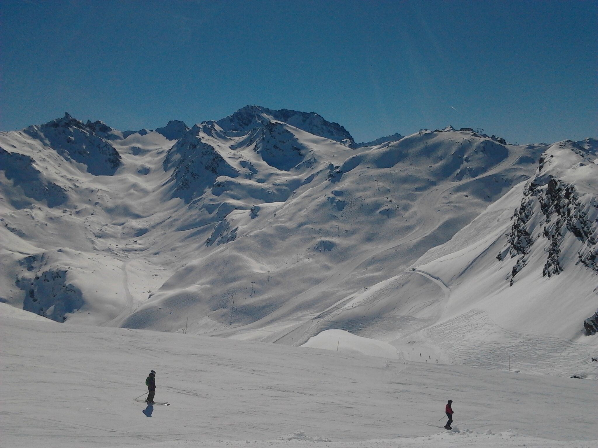 Un paysage de montagne enneigé avec deux skieurs.