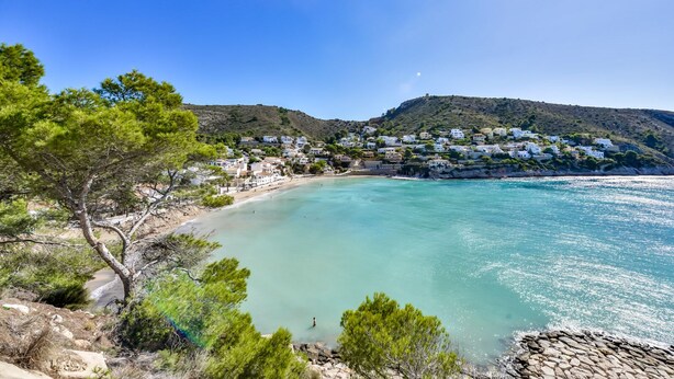 Eine Küstenstadt mit weißen Gebäuden, einem Sandstrand und einem klaren, blauen Meer.