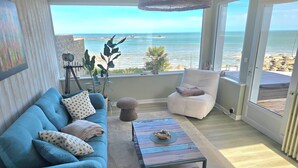 Ein Wohnzimmer mit Meerblick, ein blaues Sofa, ein Sessel, ein Couchtisch und eine Pflanze.