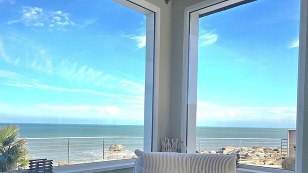 Ein Zimmer mit Meerblick, eine gepolsterte weiße Bank und ein Geländer.
