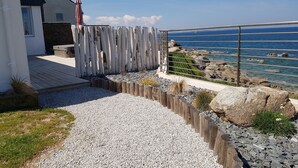 Ein Küsteneigentum mit einem Kiesweg, der zu einem Holzdeck führt, mit Blick auf das Meer.