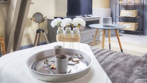 Une pièce confortable avec un lit, une petite table sur laquelle se trouve un plateau de collations, un bureau avec un ordinateur et une étagère avec des boîtes.