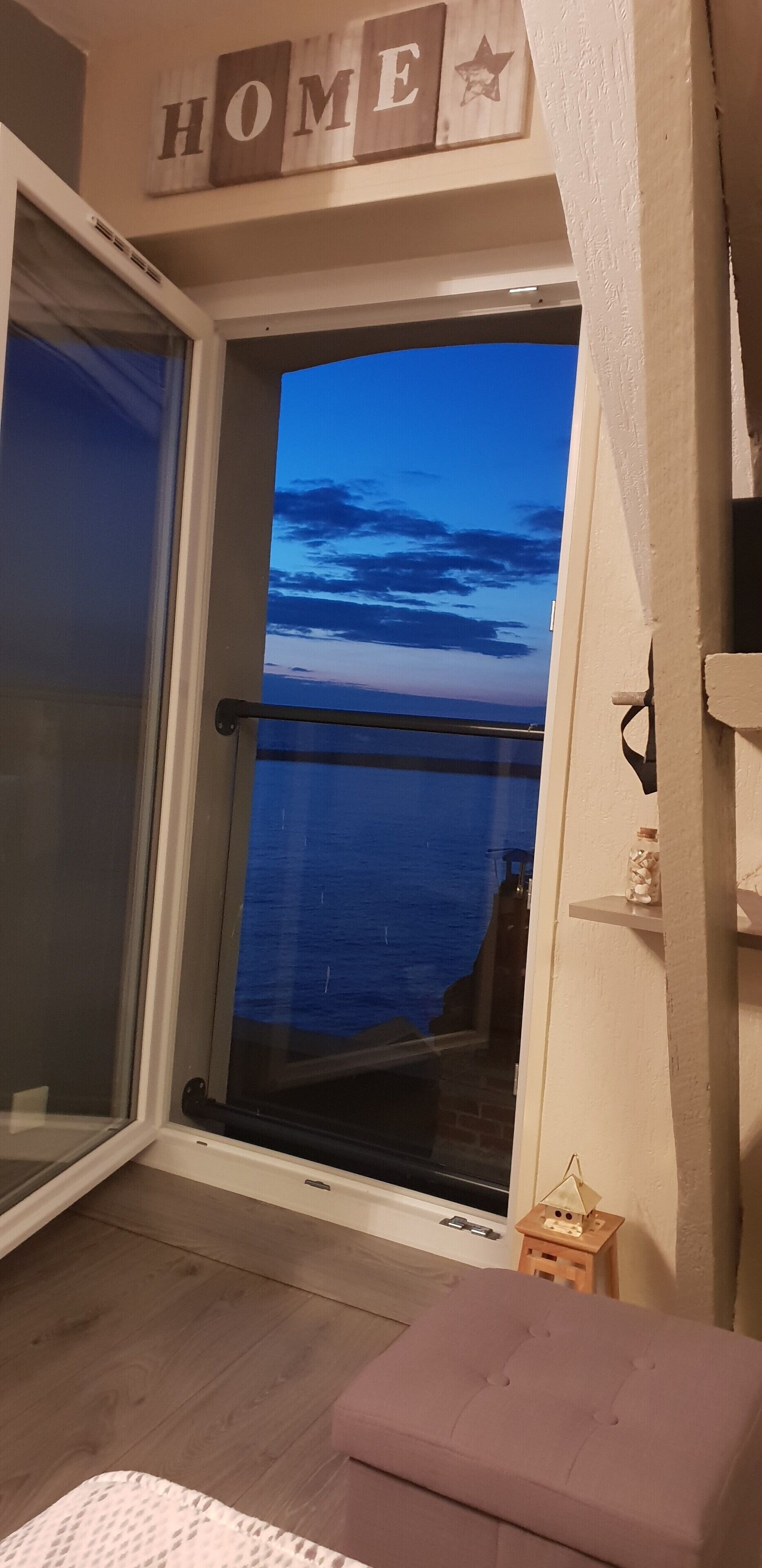 Ett rum med en skjutdörr i glas som leder ut till en balkong med utsikt över himlen.