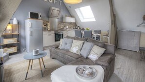 Un appartement de style loft comprenant un coin cuisine, un espace repas et un salon avec un canapé et une table basse.