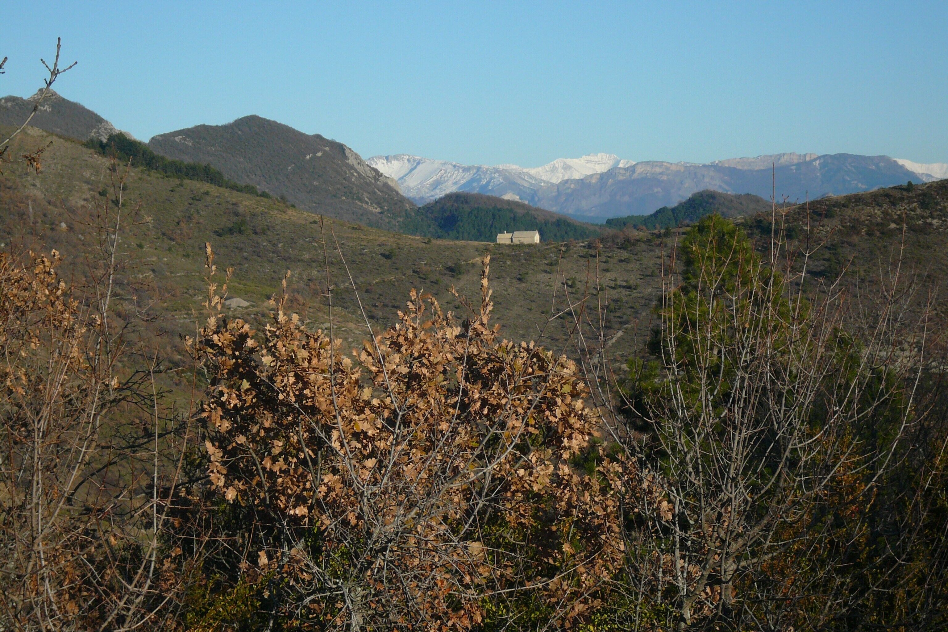 A mountainous landscape with a house in the valley.