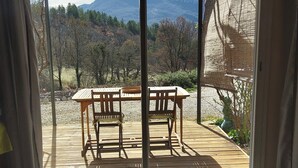 Una stanza con una porta vetrata scorrevole che dà su un patio esterno con un tavolo e sedie in legno.