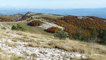 A mountainous landscape with autumn foliage, rocky terrain, and distant mountain ranges.