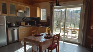 Una cucina con mobili in legno, una lavastoviglie in acciaio inossidabile e un'area pranzo con tavolo apparecchiato per due.