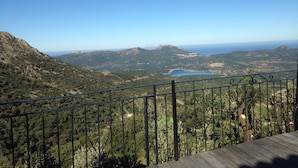 A scenic view from a balcony with a metal railing, overlooking a mountainous landscape with a lake and distant hills. - LUXURY VILLA with exceptional panoramic views, a pool, and ocean views (Speloncato)