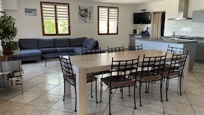 A modern living space with a dining area, sofa, TV, kitchen, and large windows. - LUXURY VILLA with exceptional panoramic views, a pool, and ocean views (Speloncato)