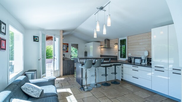 A modern kitchen with a central island, bar stools, and a seating area with a sofa. - Large villa, 6 to 15 people on the edge of the forest and river with heated pool (Cotignac)