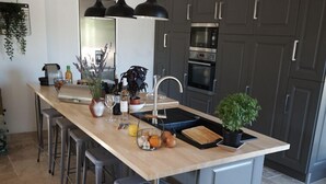 A modern kitchen with a central island, bar stools, a sink, and a built-in oven. - 2 DUPLEX   1 STUDIO IN A WONDERFUL AND PEACEFUL PLACE (Maubec)