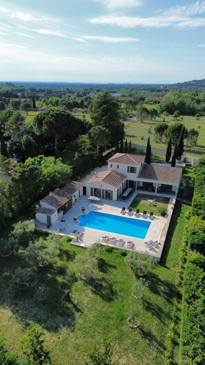 A large, modern house with a swimming pool, surrounded by lush greenery and trees. - Spacious Luberon Villa with Pool, Orchard & Panoramic Mountain Views, A/C (Maubec)