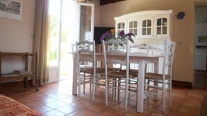 A dining area with a white table and chairs, a cabinet with glass doors, and a clock on the wall.