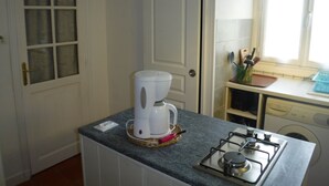 A kitchen with a coffee maker, a gas stove, and a washing machine.