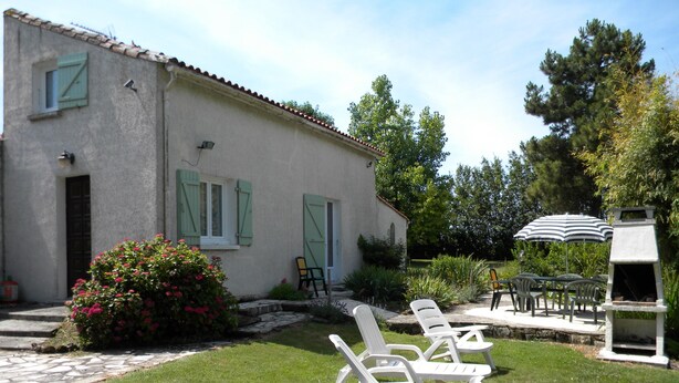 A house with a garden, outdoor seating, and a barbecue area.