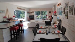 Une cuisine moderne avec un coin repas, de grandes fenêtres et une vue sur l’extérieur.