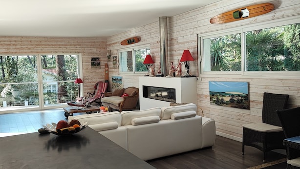Un salon moderne avec une cheminée, de grandes fenêtres et une vue sur les arbres.