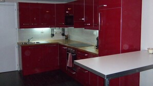 Una cocina pequeña con gabinetes rojos, un fregadero, una estufa y una encimera.