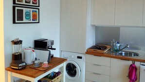 A compact kitchen with white cabinets, a washing machine, a toaster, and a coffee maker on a wooden countertop. - Old Town of Lisbon, stunning 180º view of Castelo, 3-room apartment with terrace (Lisbonne)