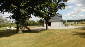 A backyard with a swing set, a small shed, and a lawn.