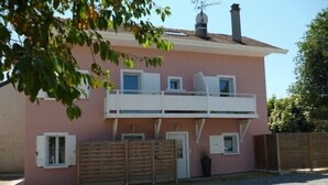 A two-story pink house with a balcony, a wooden gate, and a gravel driveway. - Studio with garden very close to the center of Thonon Baths (Thonon-Les-Bains)