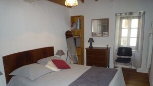 Ein Schlafzimmer mit Bett, Schreibtisch, Stuhl, Bücherregal und Fenster.