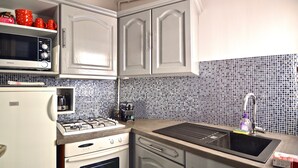 Una cocina con gabinetes blancos, microondas, estufa y lavamanos.