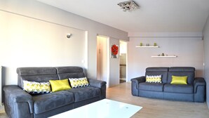 Una sala moderna con dos sofás grises, una mesa de centro blanca y cojines decorativos.