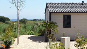 A small building with a tiled roof, surrounded by gravel and various plants.