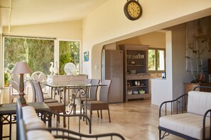 Un comedor amplio con una mesa y sillas, un reloj en la pared, y vistas al exterior.