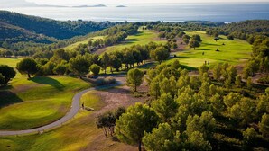 A golf course with a winding path, surrounded by dense trees and hills in the background. - Studio Seaside - Saint Cyr sur Mer (Les Lecques) (Saint-Cyr-sur-Mer)