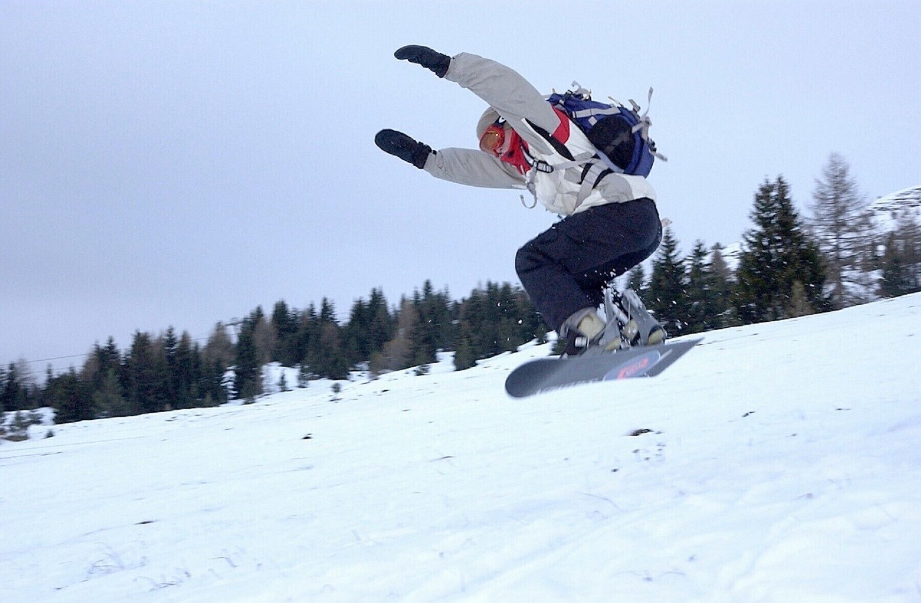 A snowboarder in mid-air performing a jump on a snowy slope.
