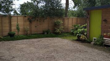 A gravel driveway leading to a wooden fence with potted plants.