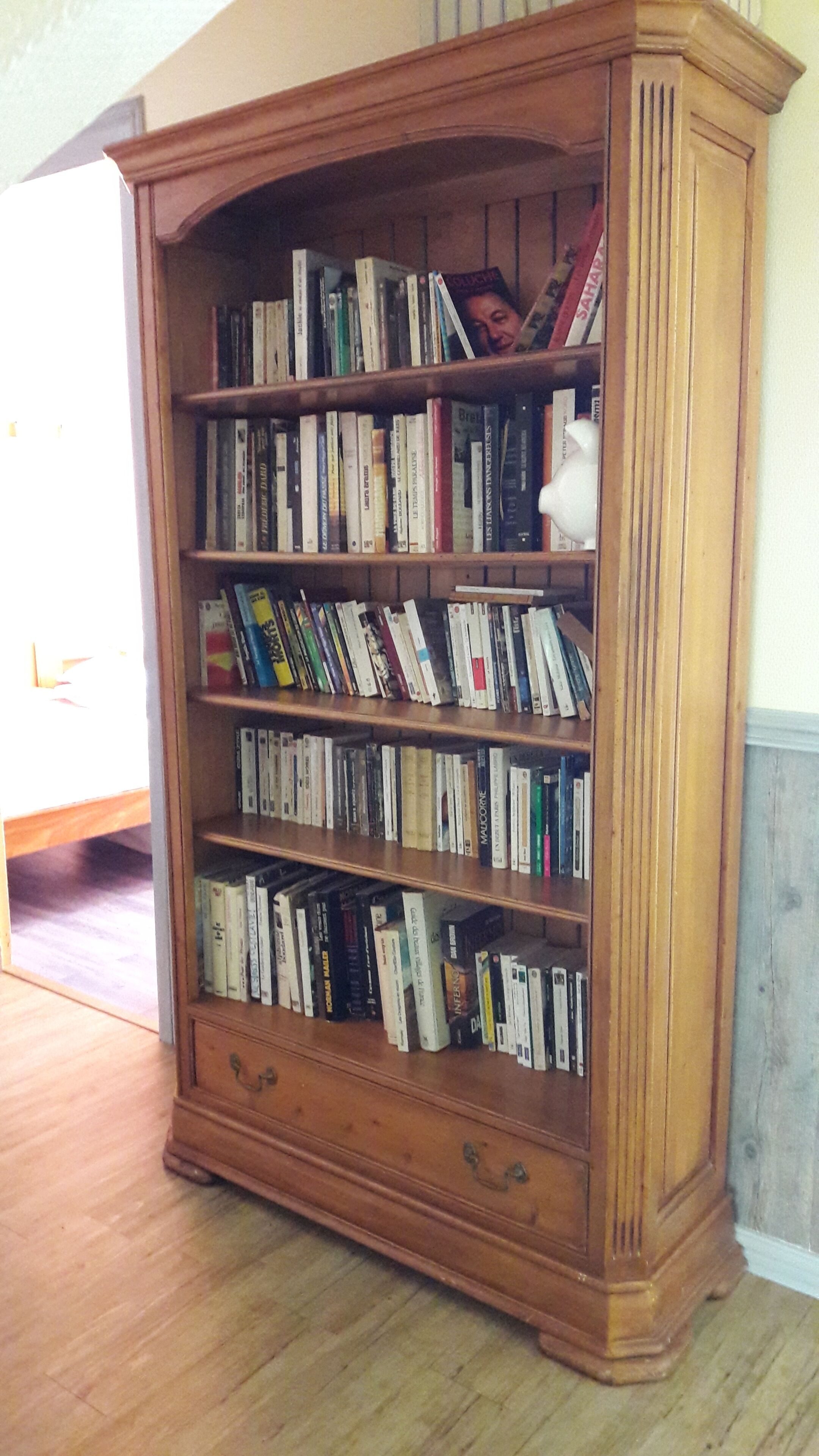 A wooden bookcase with multiple shelves filled with books.