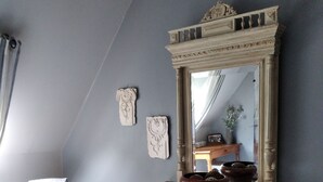 Une pièce avec une commode en bois, une chaise et un miroir au mur.