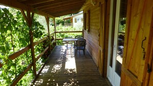Un patio in legno con tavolo e sedie, immerso nel verde.