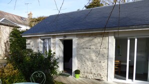 A house with a stone facade, a dark roof, and a small garden with a table and chairs. - Charming country house (Andonville)