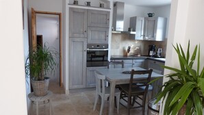 Une cuisine compacte comprenant une table et des chaises, un four encastré et un évier.